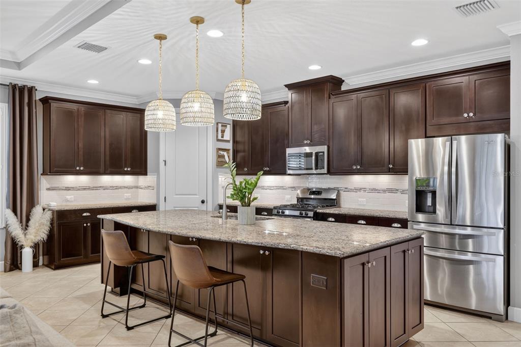 A kitchen with dark wood cabinets, granite countertops, a large island, and stainless steel appliances — 13202 PRIMA DRIVE, BRADENTON, FL