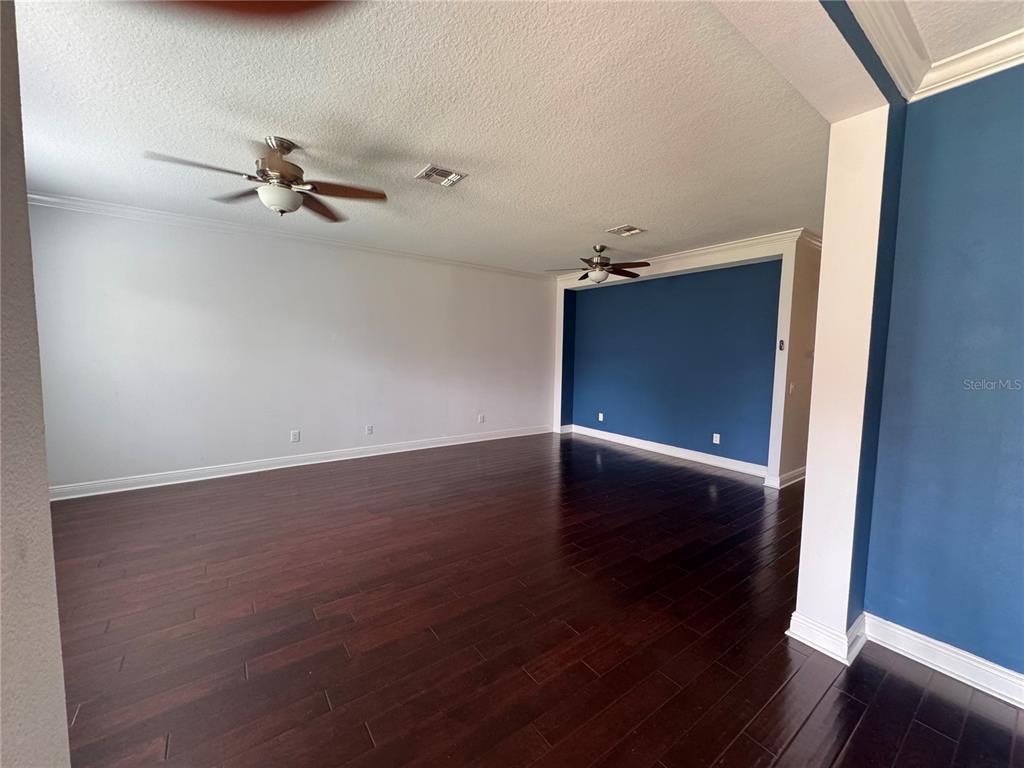 An empty room features dark hardwood floors, white walls, and a blue accent wall — 5335 FACTORS WALK DRIVE, SANFORD, FL