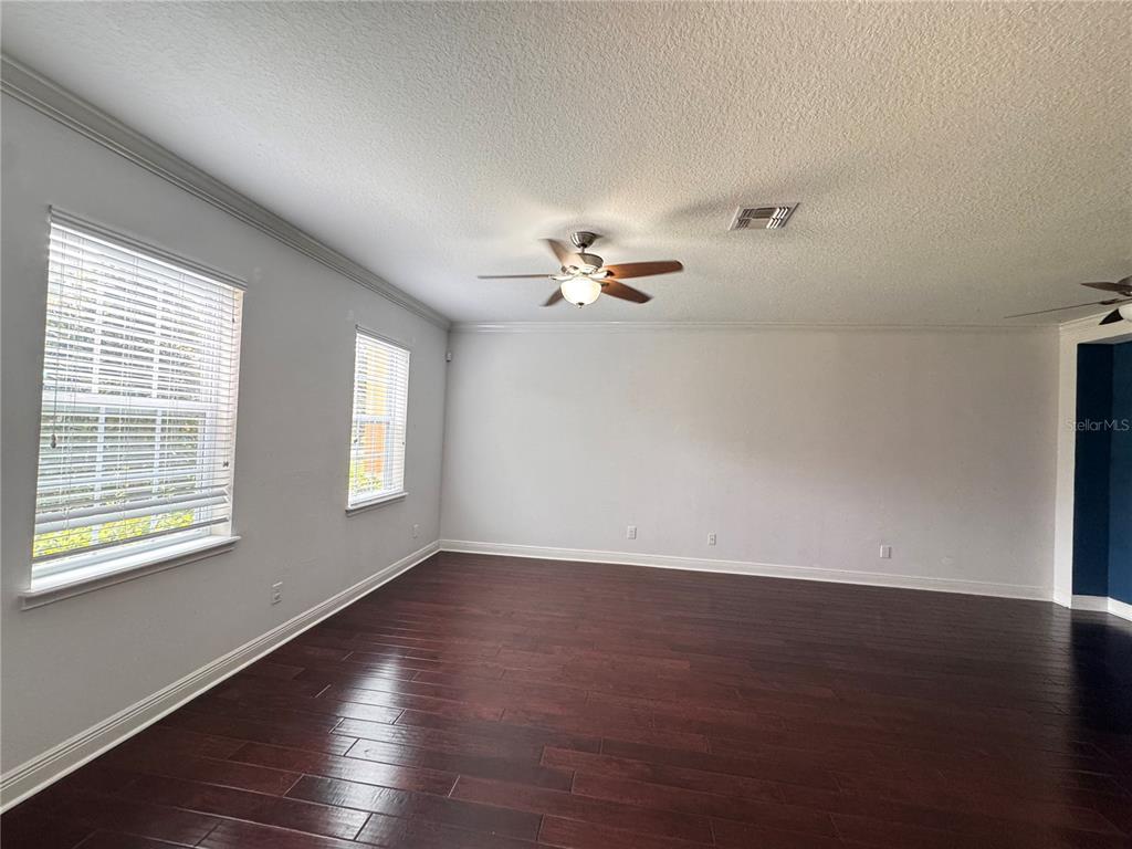 An empty living room features dark hardwood floors, light gray walls, and a ceiling fan — 5335 FACTORS WALK DRIVE, SANFORD, FL