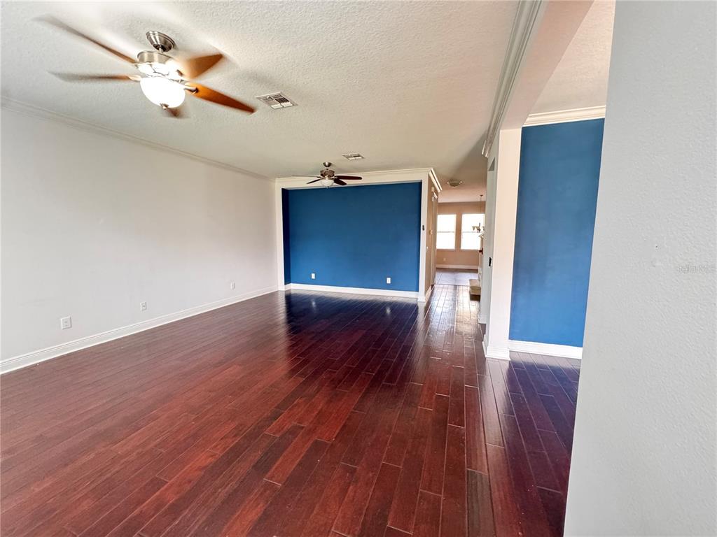 An open living area features dark hardwood floors, white walls, and a blue accent wall — 5335 FACTORS WALK DRIVE, SANFORD, FL