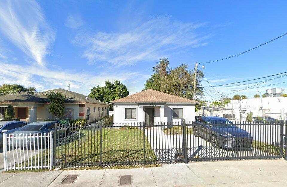 A single-story house with a concrete driveway, gated entrance, and a brown shingled roof — 2221 NW 57th St, Miami FL 33142, MIAMI, FL