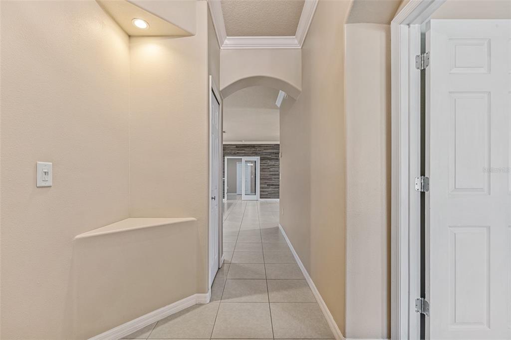 A tiled hallway leads through an arched doorway toward a room with a wood-paneled wall — 1234 CAP DIVILLE AVENUE, PORT ORANGE, FL