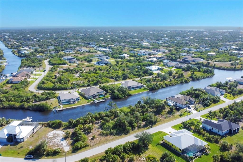 An aerial view shows houses along a canal in a residential neighborhood with lush vegetation — 9984 WINNIPEG STREET, PORT CHARLOTTE, FL
