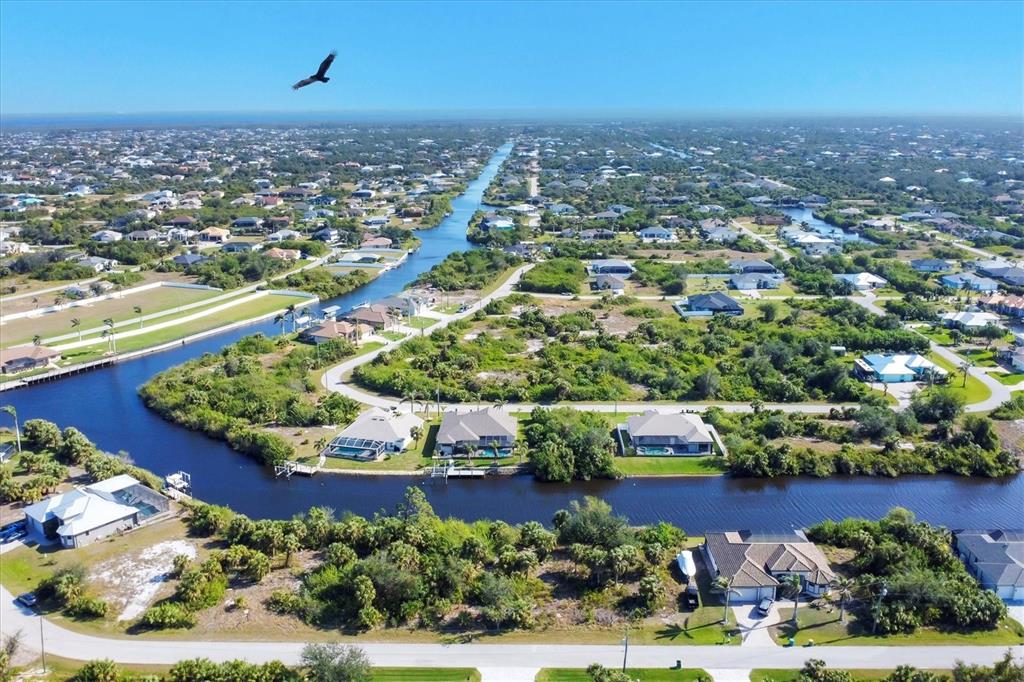 An aerial view shows houses along a canal in a residential neighborhood with a bird flying — 9984 WINNIPEG STREET, PORT CHARLOTTE, FL