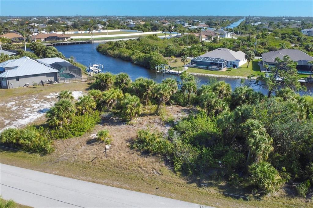 An aerial view of a vacant waterfront lot with palm trees and nearby residential homes — 9984 WINNIPEG STREET, PORT CHARLOTTE, FL