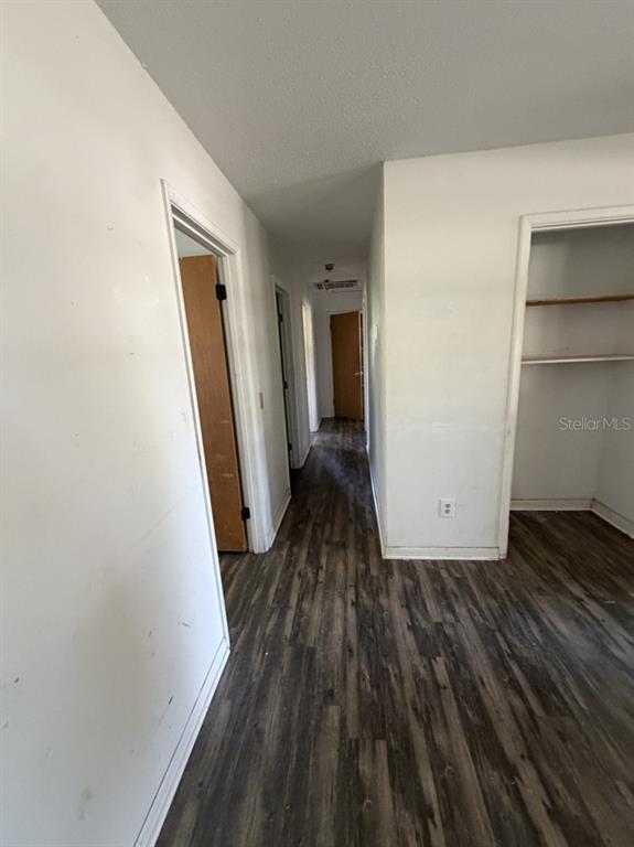 A hallway with wood-look flooring leads to a doorway, with a closet on the right — 3145 FLETCHER AVENUE, LAKELAND, FL