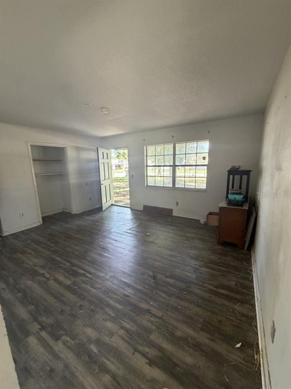 An empty room features wood-look flooring, a closet, a window, and an exterior door — 3145 FLETCHER AVENUE, LAKELAND, FL