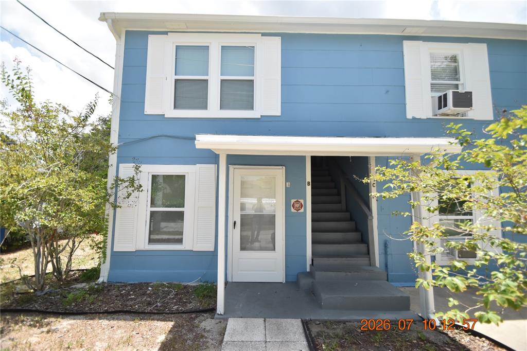 A two-story blue building features a white front door, stairs, and white-trimmed windows — 1156 SUNSET POINT ROAD UNIT A, CLEARWATER, FL