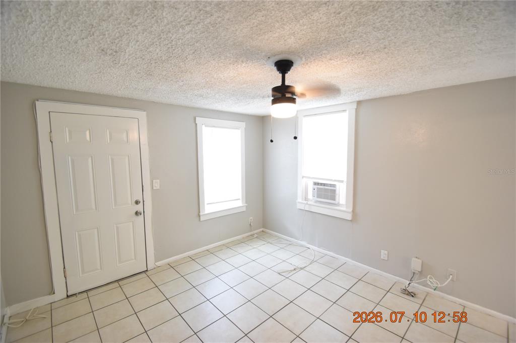 A room with white tile floors, light gray walls, a ceiling fan, and two windows — 1156 SUNSET POINT ROAD UNIT A, CLEARWATER, FL