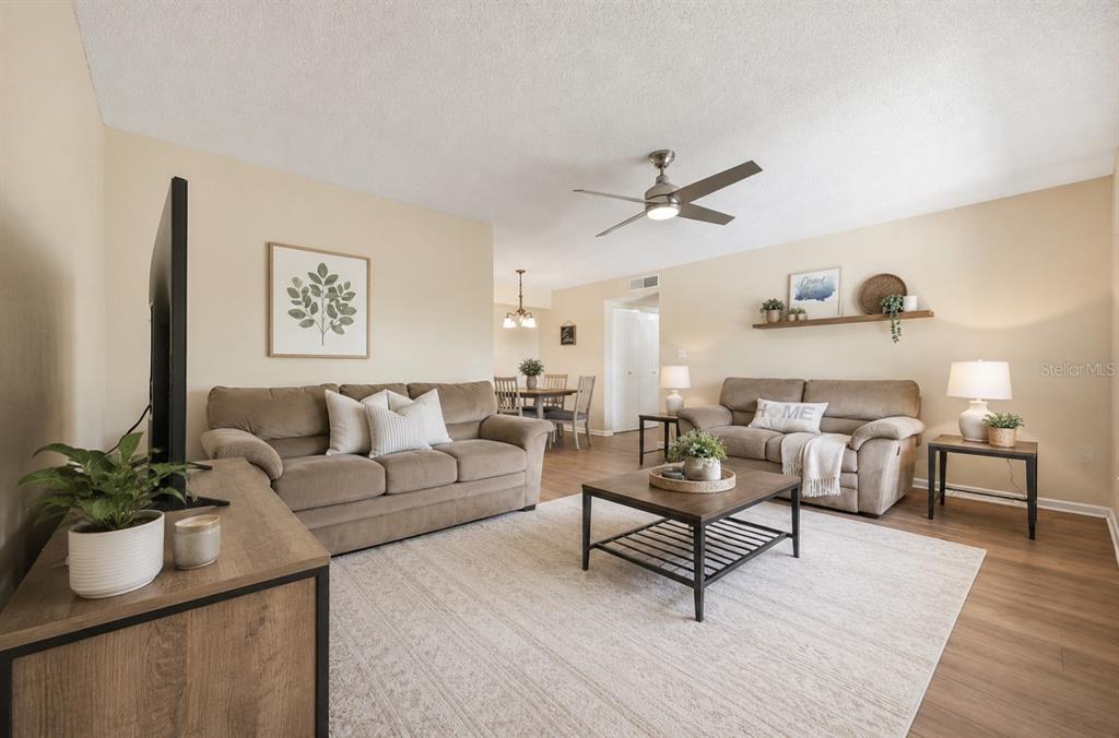 A living room features two tan sofas, a coffee table, and a dining area beyond — 2690 CORAL LANDINGS BOULEVARD UNIT 133, PALM HARBOR, FL