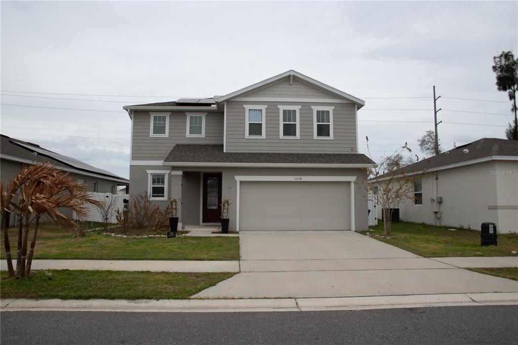 A two-story, light gray suburban house with a two-car garage and a concrete driveway — 1054 HEIRLOOM DRIVE, HAINES CITY, FL