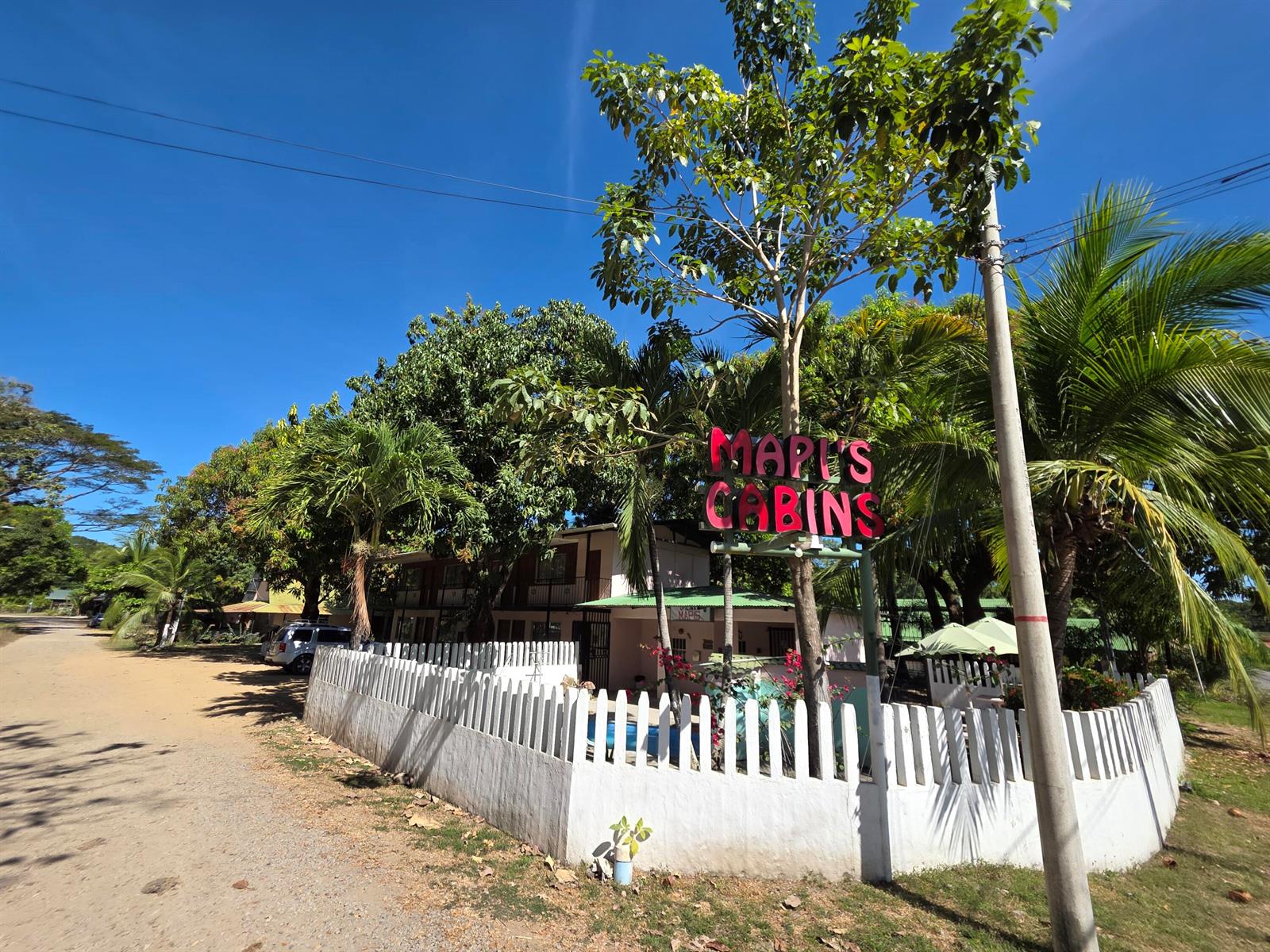 A white picket fence surrounds the exterior of Mapi's Cabins under a bright blue sky — 3.5km W From Paquera, 00000, FL