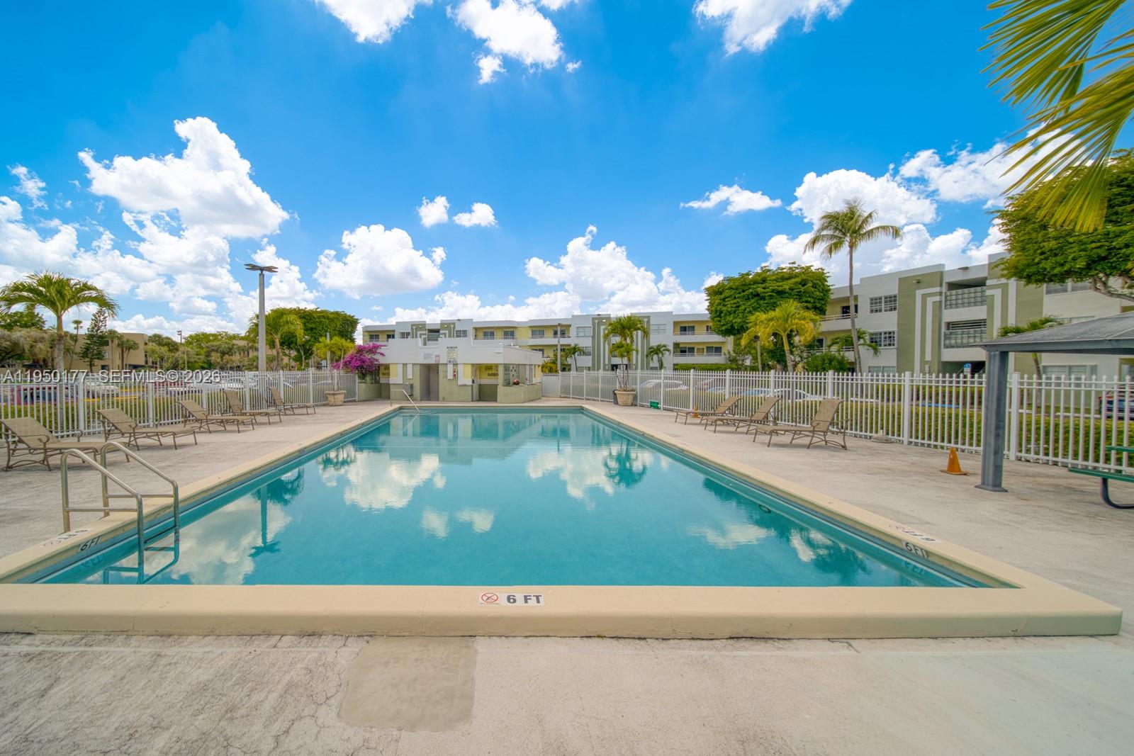 A rectangular outdoor swimming pool is surrounded by a concrete deck and white metal fencing — 10795 SW 108th Ave # 304, Miami FL 33176, MIAMI, FL