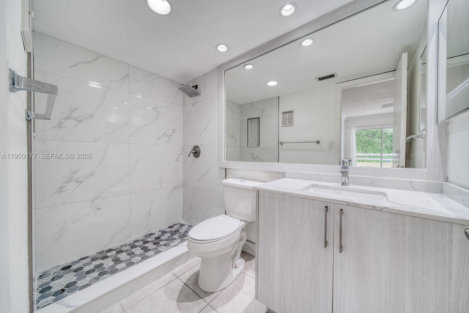 A bathroom features a walk-in shower with marble-look tiles, a vanity, and a toilet — 10795 SW 108th Ave # 304, Miami FL 33176, MIAMI, FL