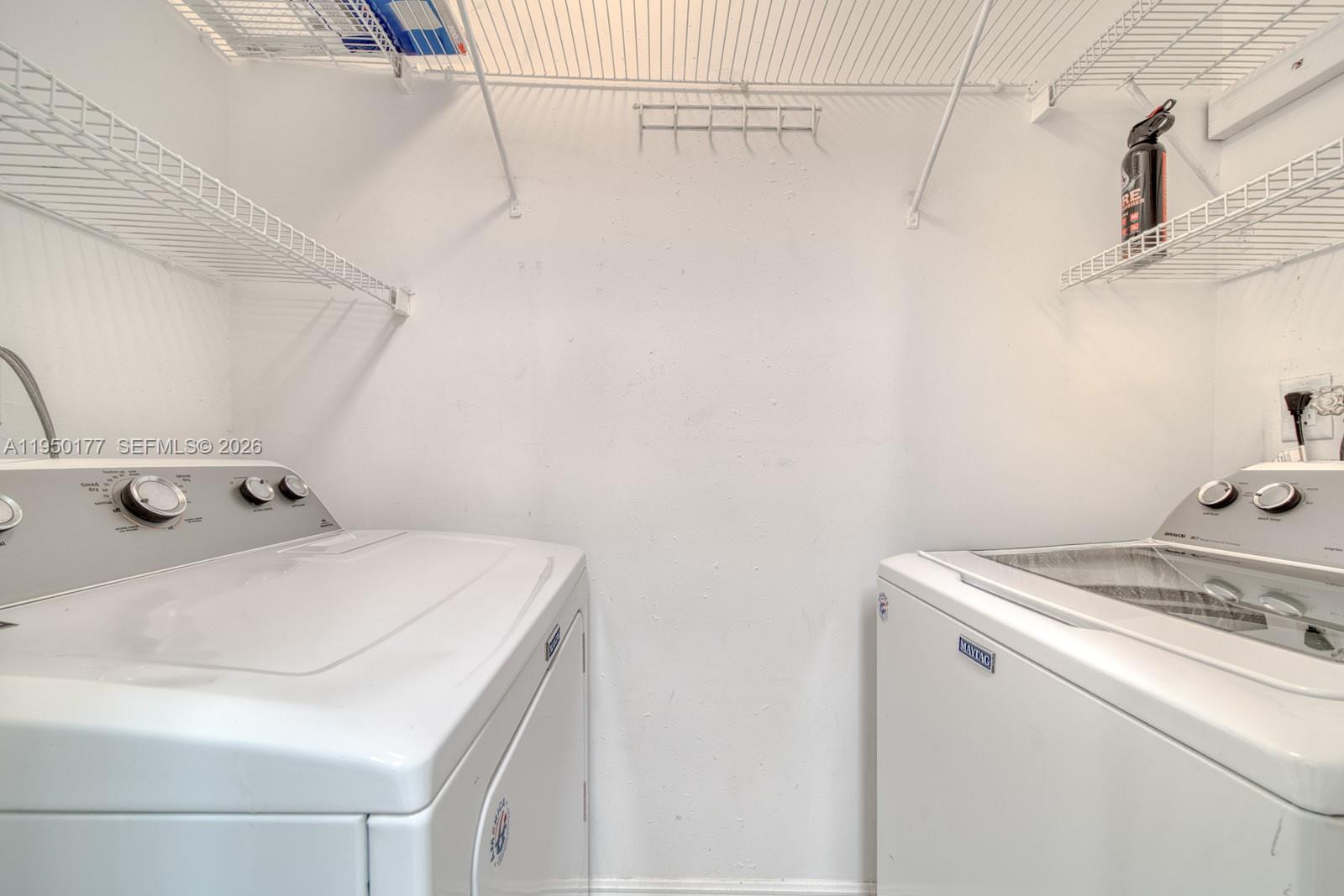 A laundry closet features a white washer and dryer beneath wire shelving — 10795 SW 108th Ave # 304, Miami FL 33176, MIAMI, FL