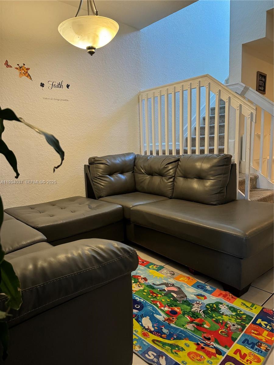 A living room features a gray sectional sofa on a colorful alphabet rug near stairs — 1043 SE 23rd Ave, Homestead FL 33035, HOMESTEAD, FL