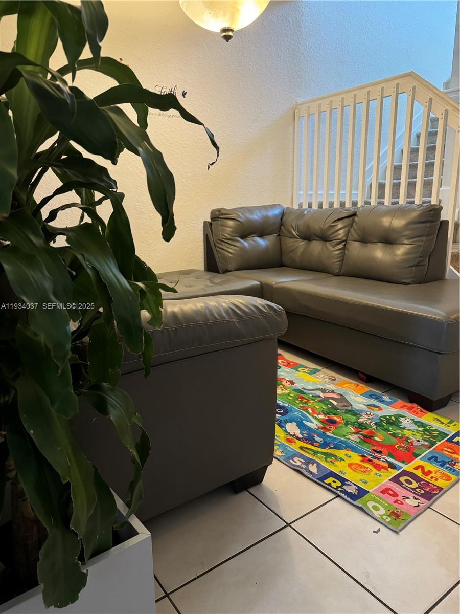 A living room features a gray sectional sofa, a tiled floor, and a children's alphabet rug — 1043 SE 23rd Ave, Homestead FL 33035, HOMESTEAD, FL