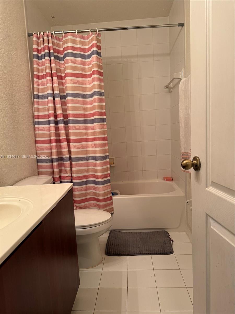 A bathroom features a white vanity, a toilet, and a shower-tub combo with a striped curtain — 1043 SE 23rd Ave, Homestead FL 33035, HOMESTEAD, FL
