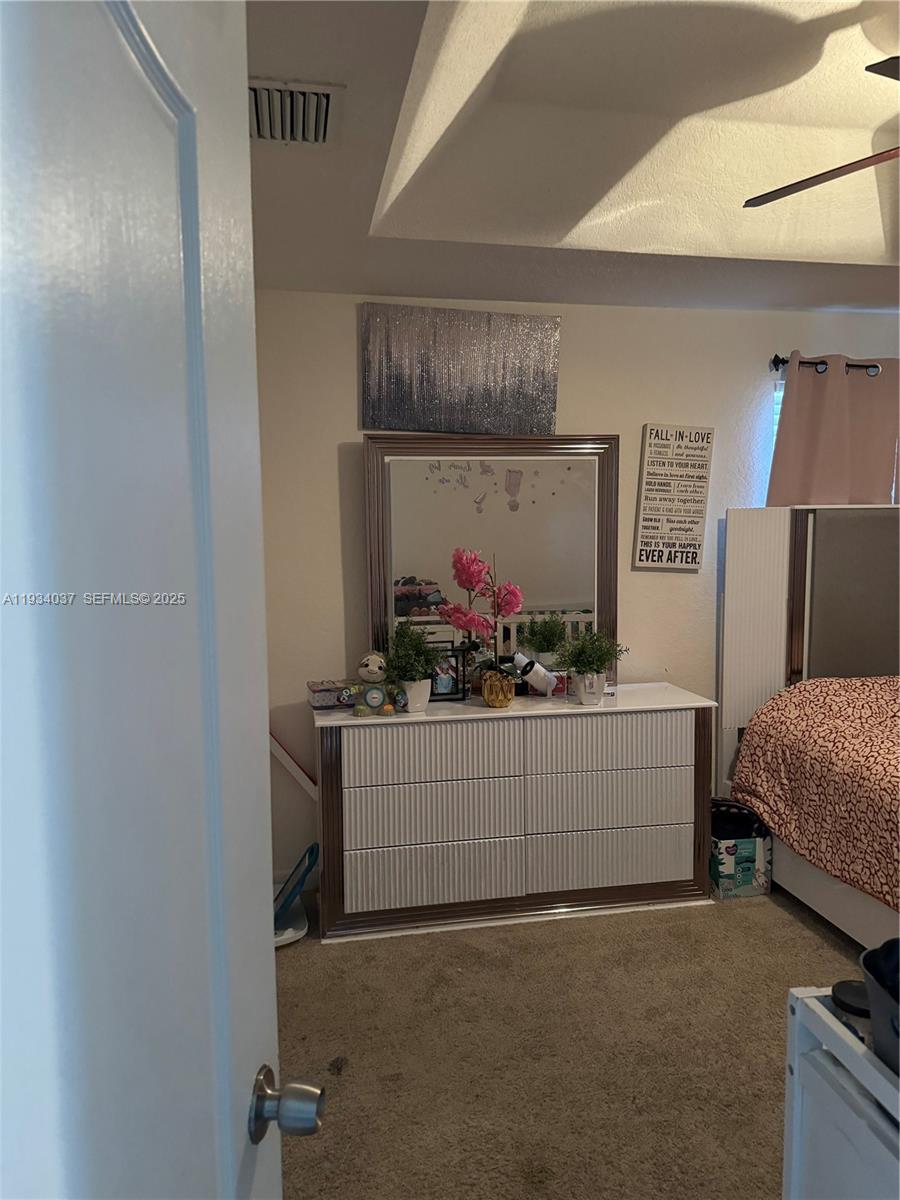 A bedroom features a white six-drawer dresser with a mirror, a bed, and wall art — 1043 SE 23rd Ave, Homestead FL 33035, HOMESTEAD, FL