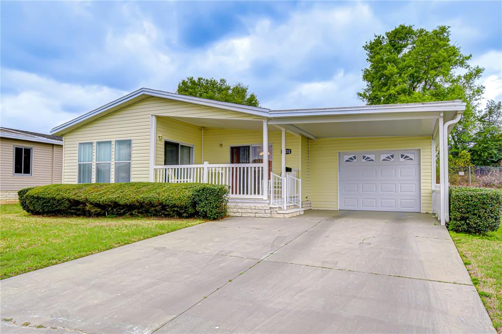 A light yellow single-story house features a concrete driveway, a carport, and a front porch — 37232 NEUKOM AVENUE, ZEPHYRHILLS, FL
