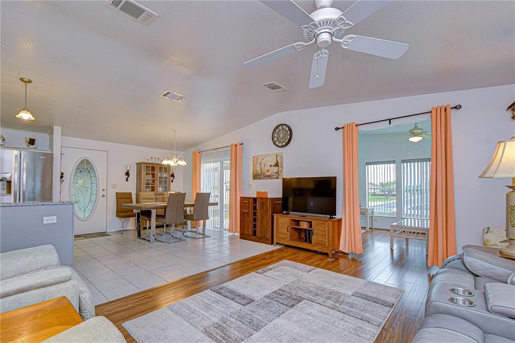 An open-concept living and dining area features tile and wood flooring, a ceiling fan, and furniture — 37232 NEUKOM AVENUE, ZEPHYRHILLS, FL