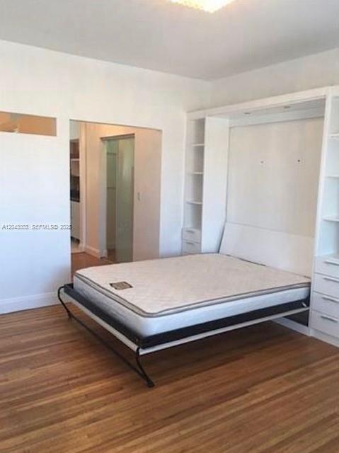 A bedroom features a white Murphy bed with built-in shelving on hardwood floors — 503 74th St # B3, Miami Beach FL 33141, MIAMI BEACH, FL