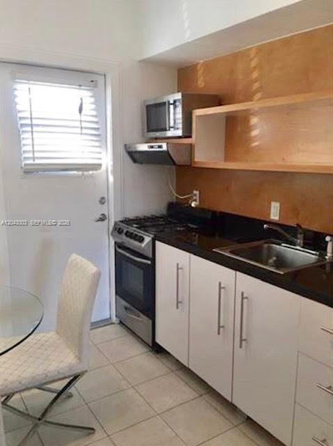 A kitchen features white cabinets, black countertops, a stainless steel stove, and a glass door — 503 74th St # B3, Miami Beach FL 33141, MIAMI BEACH, FL
