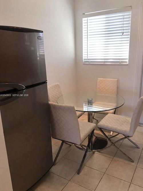 A small dining area features a glass table, four upholstered chairs, and a stainless refrigerator — 503 74th St # B3, Miami Beach FL 33141, MIAMI BEACH, FL
