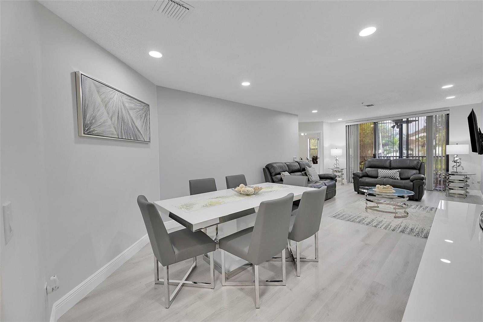 A dining area with a white table and grey chairs opens into a living room — 5133 Brisata Circle # P, Boynton Beach FL 33437, BOYNTON BEACH, FL