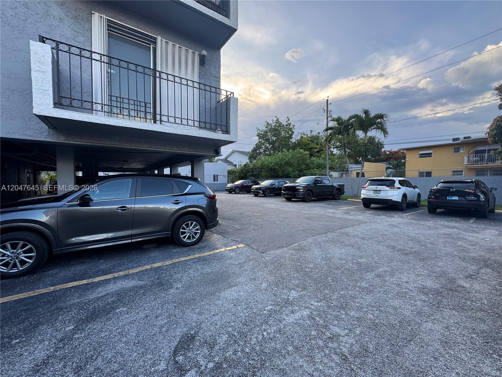 An outdoor parking lot sits beneath a building balcony with a dark metal railing — 1933 SW 7th St # 504, Miami FL 33135, MIAMI, FL