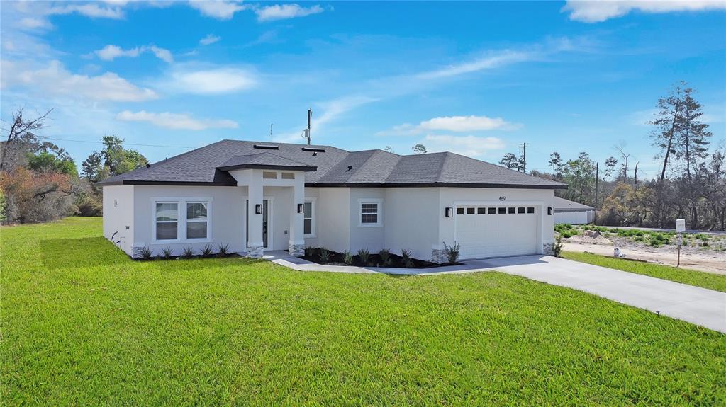 A single-story house with a white stucco exterior, dark roof, and attached two-car garage — 469 MARION OAKS LANE, OCALA, FL