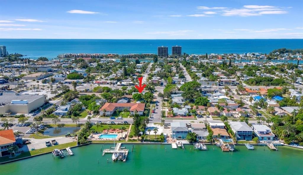 An aerial view shows a coastal neighborhood with a red arrow pointing toward a house — 340 78TH AVENUE, ST PETE BEACH, FL