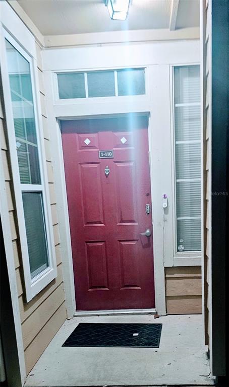 A red front door with a house number sign sits at the entrance of a home — 1101 VINTAGE VILLAGE LANE UNIT 110, OCOEE, FL