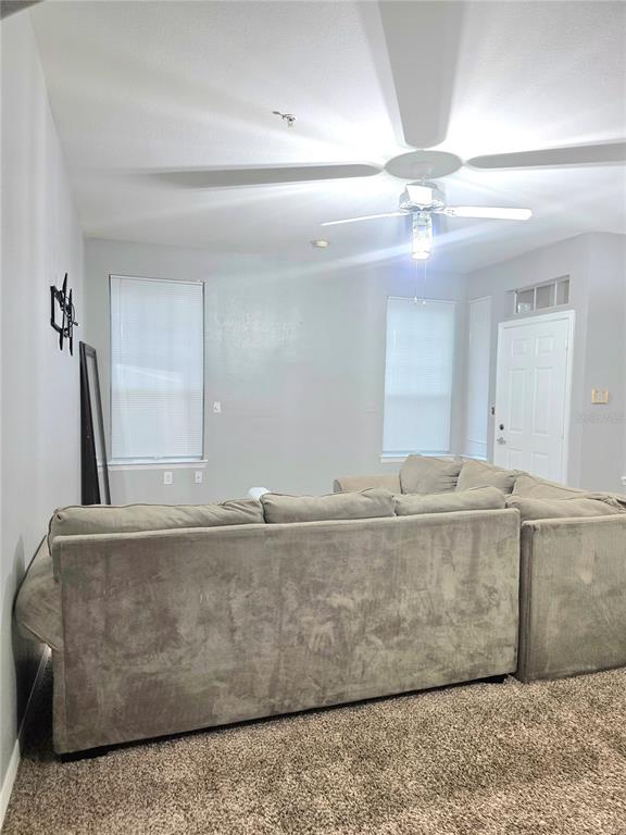 A living room features a large sectional sofa, carpeted flooring, and a ceiling fan — 1101 VINTAGE VILLAGE LANE UNIT 110, OCOEE, FL