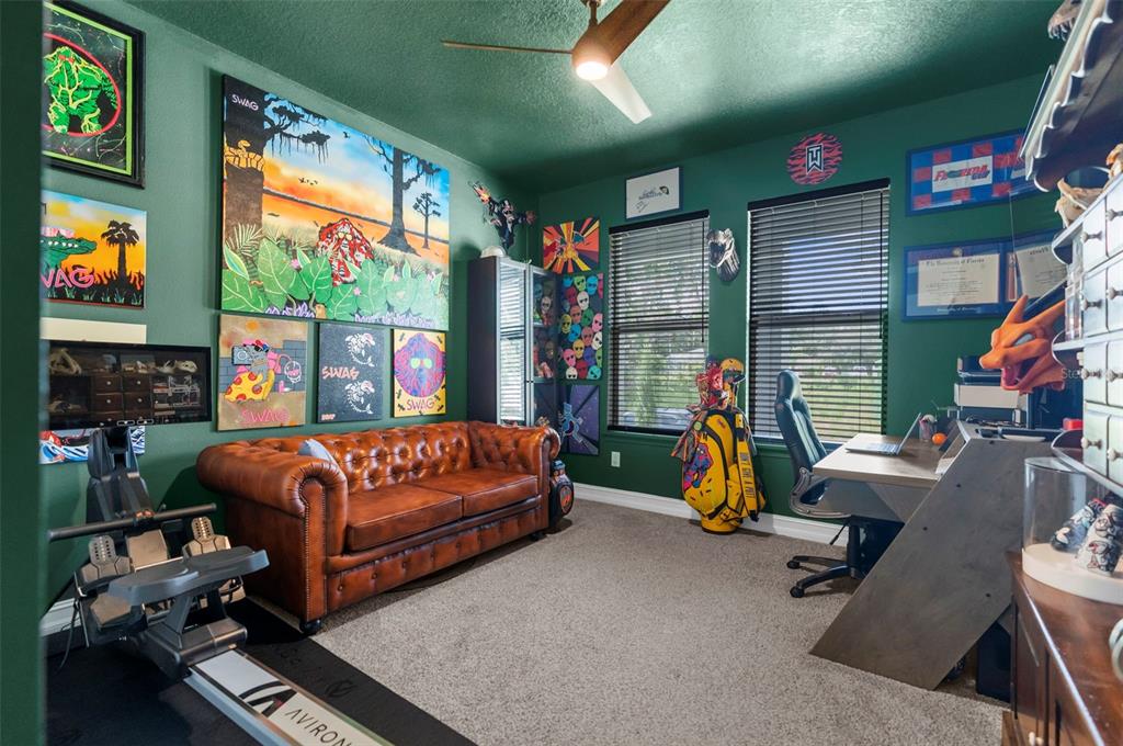 A green-walled home office features a brown leather sofa, a desk, and a rowing machine — 5100 WESTLAKE BOULEVARD, DADE CITY, FL