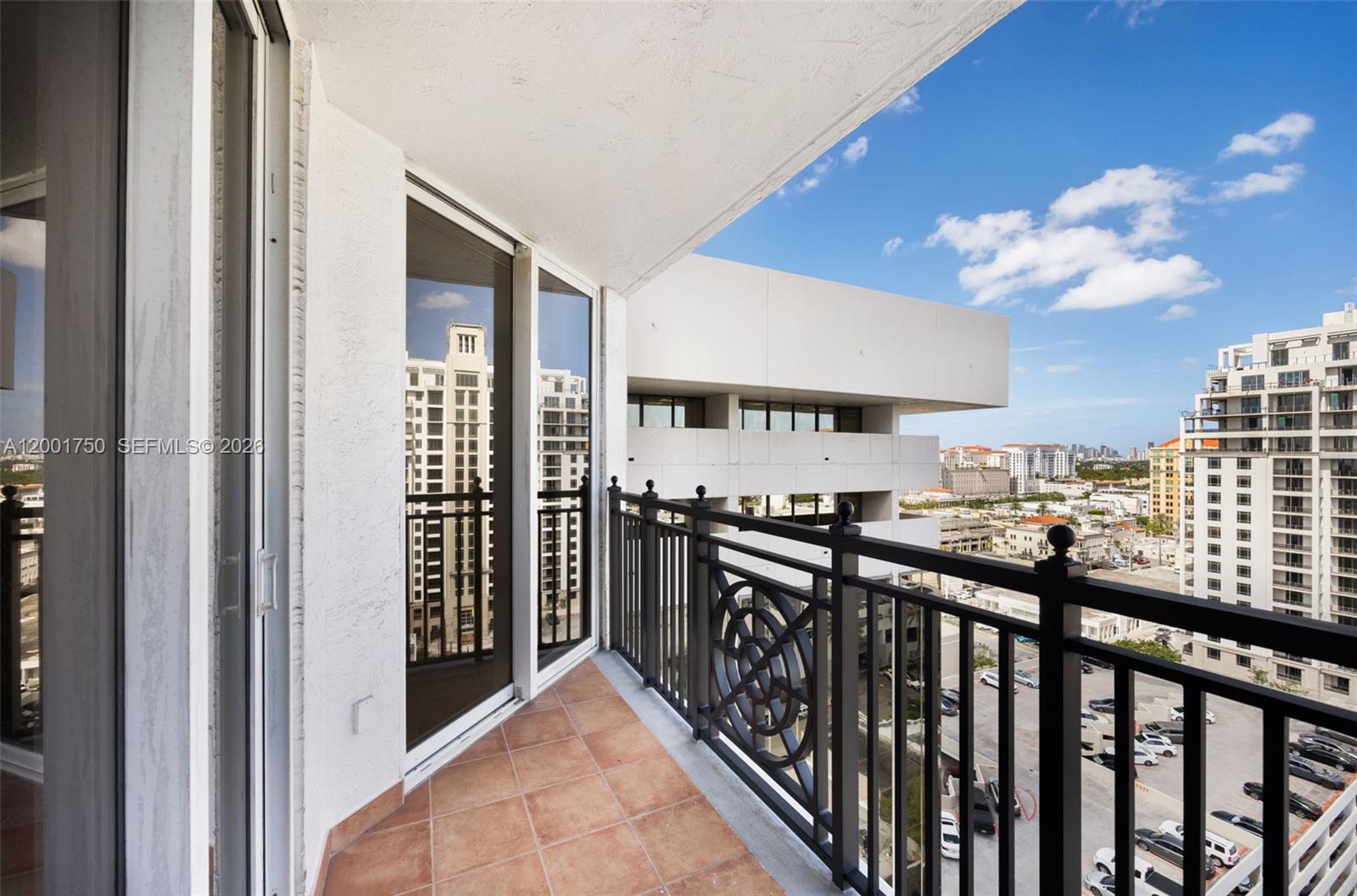 A tiled balcony features a black metal railing overlooking a city street and buildings — 357 Almeria Ave # 1507, Coral Gables FL 33134, CORAL GABLES, FL