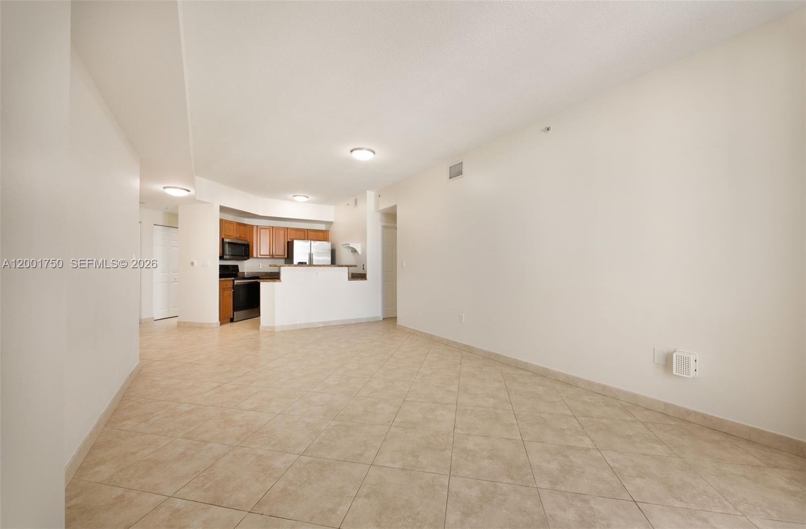 An open-concept living area features beige tile flooring and a kitchen with wooden cabinets — 357 Almeria Ave # 1507, Coral Gables FL 33134, CORAL GABLES, FL