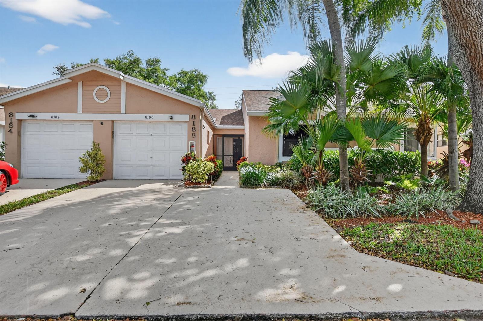 A single-story house with a two-car garage, a concrete driveway, and lush tropical landscaping — 8188 Summerbreeze Lane, Boca Raton FL 33496, BOCA RATON, FL