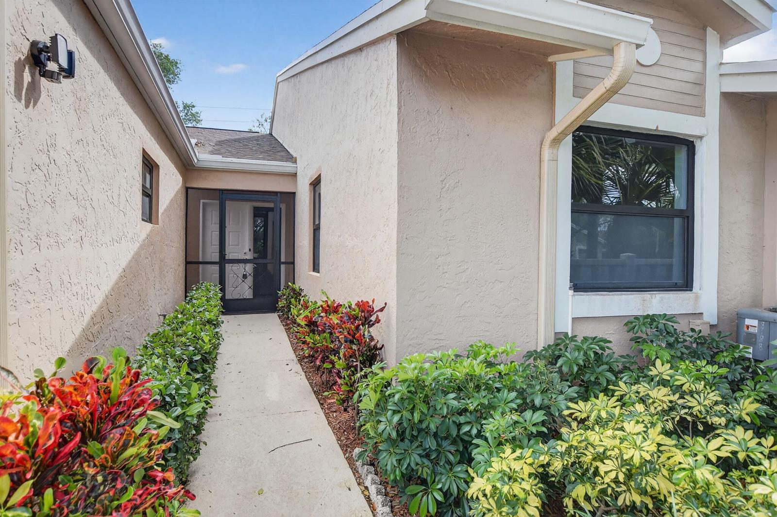A concrete walkway leads to a screened front door entrance flanked by lush landscaping — 8188 Summerbreeze Lane, Boca Raton FL 33496, BOCA RATON, FL