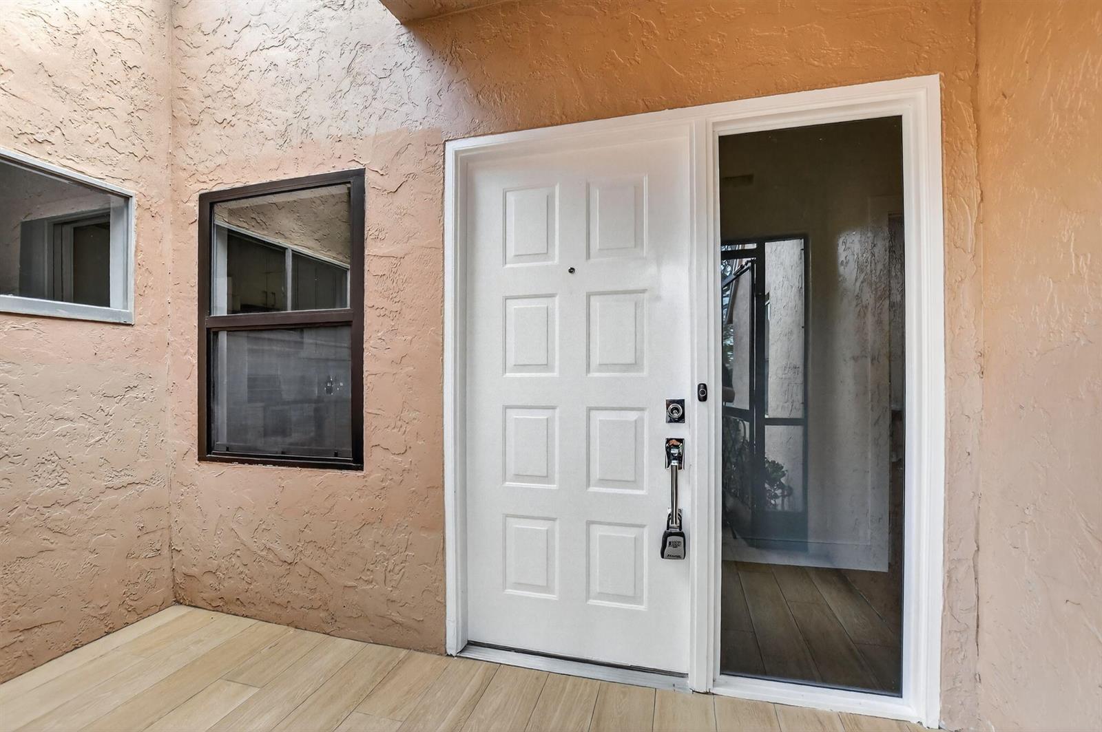 A white front door with a side window and a lockbox sits on a tiled porch — 8188 Summerbreeze Lane, Boca Raton FL 33496, BOCA RATON, FL