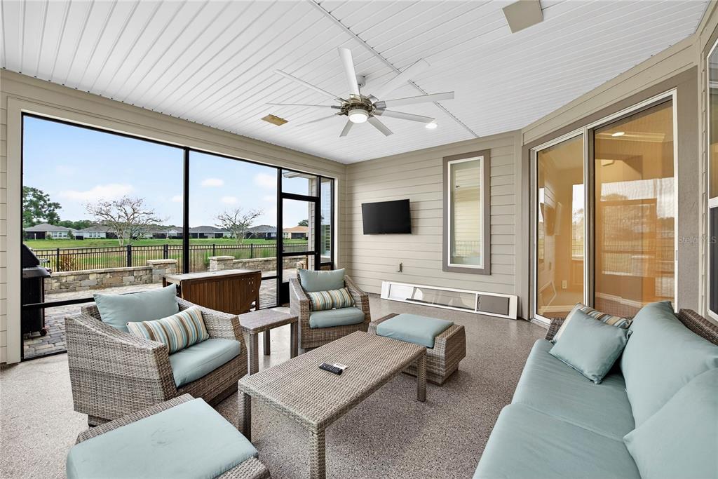 A screened-in patio features wicker furniture, a ceiling fan, a wall-mounted television, and outdoor views — 5575 NW 43RD LANE ROAD, OCALA, FL