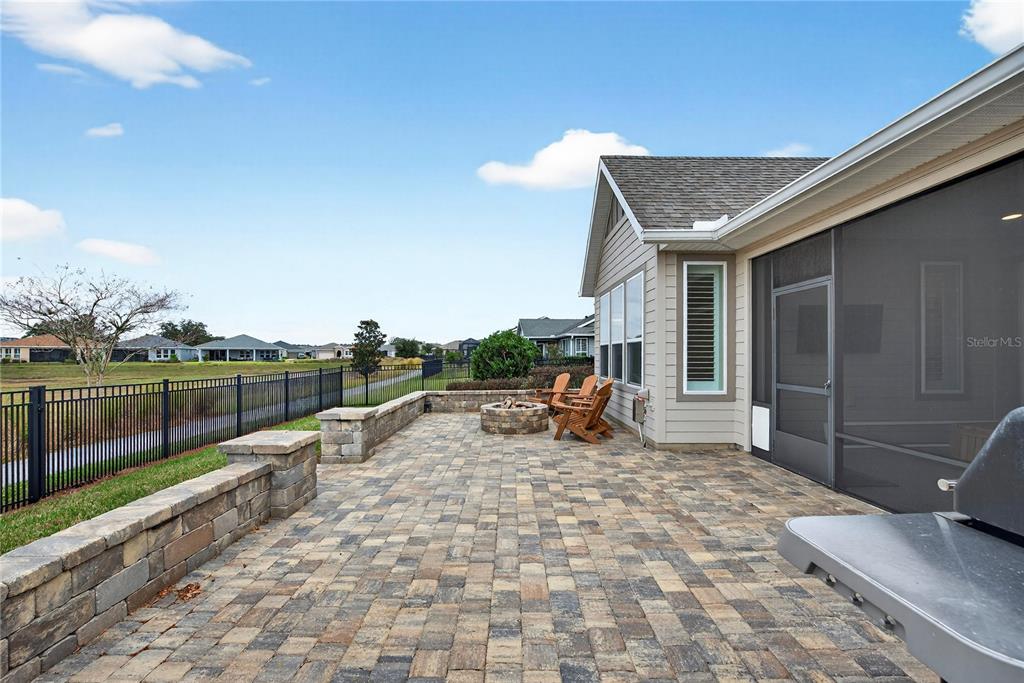 A paved patio features a stone fire pit, wooden chairs, and a low retaining wall — 5575 NW 43RD LANE ROAD, OCALA, FL