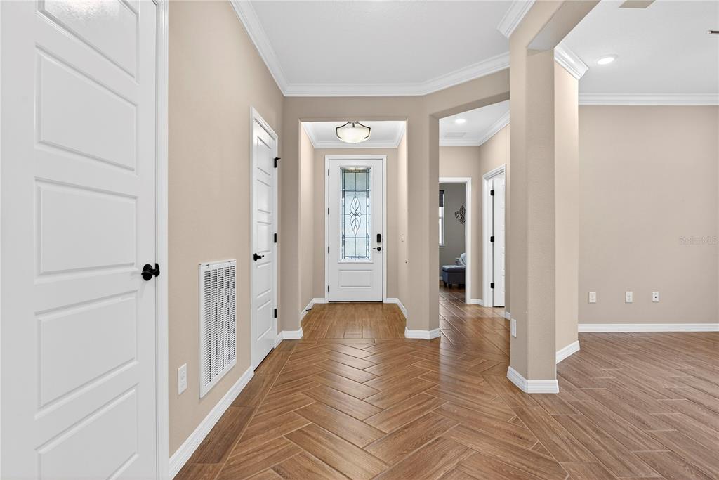 An entryway with herringbone-patterned wood-look tile flooring, white doors, and a glass-paneled front door — 5575 NW 43RD LANE ROAD, OCALA, FL