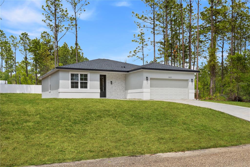 A single-story house with a white exterior, stone accent wall, and attached two-car garage — 2421 W LANDMARK DRIVE, CITRUS SPRINGS, FL
