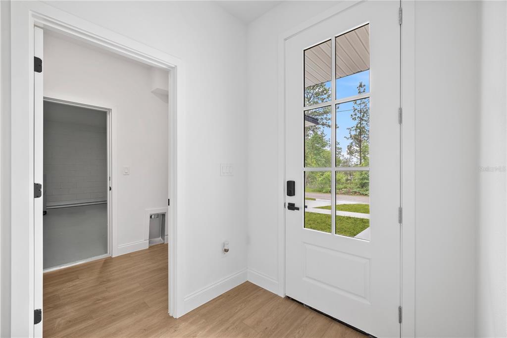 An entryway with light wood-look flooring, white walls, and a glass-paneled front door — 2421 W LANDMARK DRIVE, CITRUS SPRINGS, FL