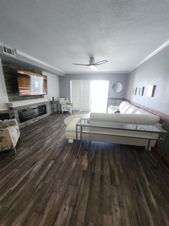 A living room features wood-look flooring, a stone fireplace with a television, and a white sofa — 1819 SHORE DRIVE S UNIT 217, SOUTH PASADENA, FL
