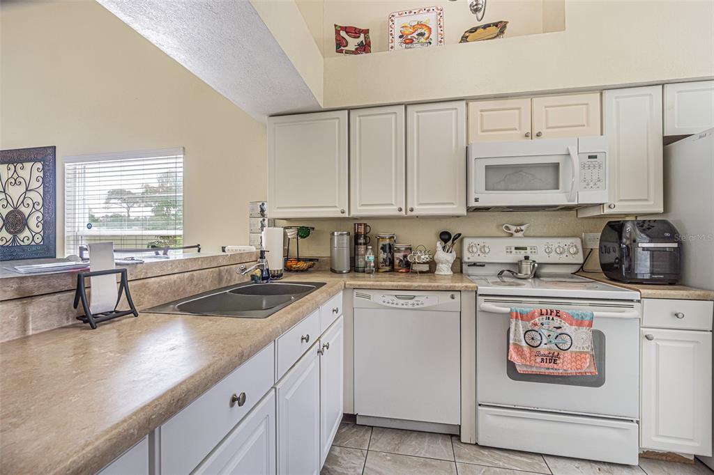 A kitchen features white cabinets, laminate countertops, a white stove, and a dishwasher — 7601 LIMEBURY COURT, TAMPA, FL
