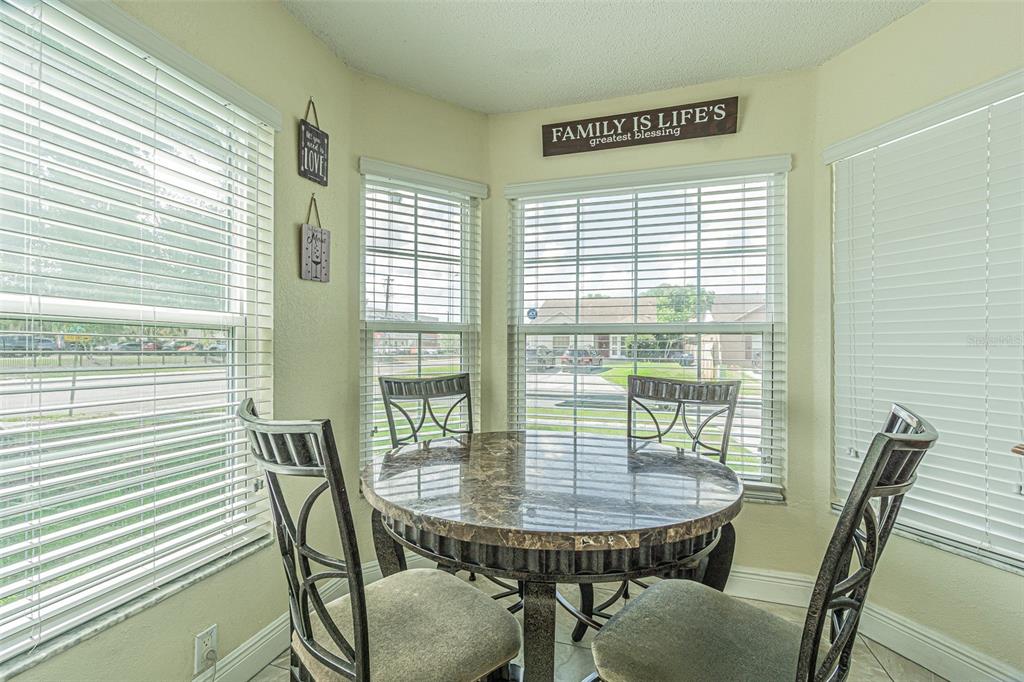 A breakfast nook features a round marble-topped table, four chairs, and windows with blinds — 7601 LIMEBURY COURT, TAMPA, FL