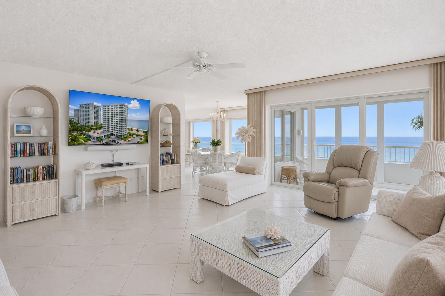 A bright living room features white wicker furniture, a television, and a balcony overlooking the ocean — 600 S Ocean Boulevard # 6010, Boca Raton FL 33432, BOCA RATON, FL