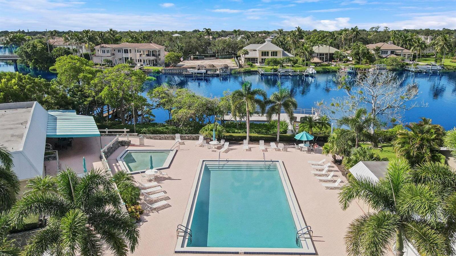 An elevated view of a rectangular swimming pool and hot tub overlooking a canal — 18419 SE Wood Haven Lane # B, Tequesta FL 33469, TEQUESTA, FL